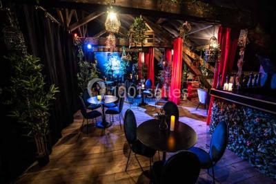 Bar décoré de plantes, bougies et éclairage tamisé, avec un robinet de bière en métal sur le comptoir.