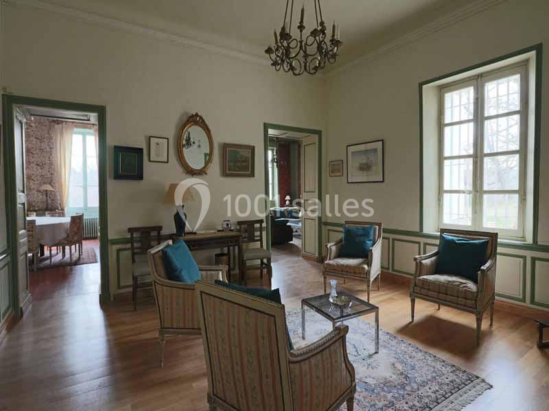 Salon lumineux avec parquet, mobilier classique, quatre fauteuils, table basse et décoration murale, vue sur deux pièces…