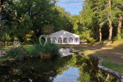 Façade d'un bâtiment illuminée par des motifs colorés, avec guirlandes lumineuses et leur reflet dans un plan d'eau.