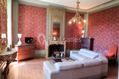 Façade d'un bâtiment illuminée par des motifs colorés, avec guirlandes lumineuses et leur reflet dans un plan d'eau.