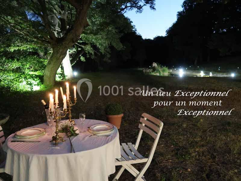 Table dressée avec chandeliers et vaisselle, installée en extérieur dans un jardin éclairé de nuit.