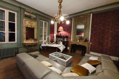 Façade d'un bâtiment illuminée par des motifs colorés, avec guirlandes lumineuses et leur reflet dans un plan d'eau.