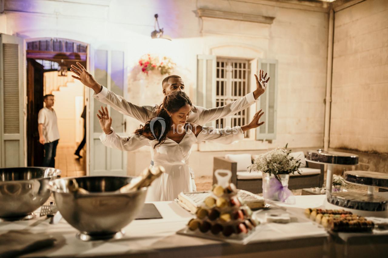 Un couple danse joyeusement devant une table dressée avec des desserts et des décorations lors d'une réception en soirée.