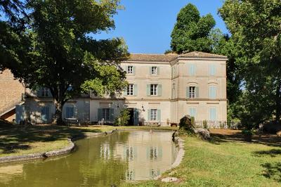 Façade d'un bâtiment illuminée par des motifs colorés, avec guirlandes lumineuses et leur reflet dans un plan d'eau.