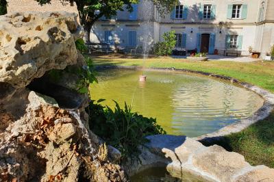 Façade d'un bâtiment illuminée par des motifs colorés, avec guirlandes lumineuses et leur reflet dans un plan d'eau.