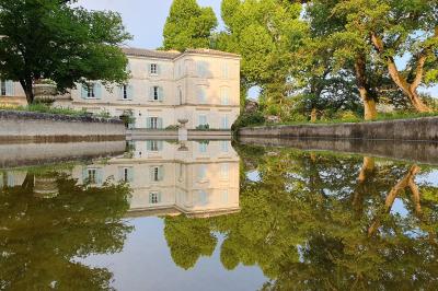Façade d'un bâtiment illuminée par des motifs colorés, avec guirlandes lumineuses et leur reflet dans un plan d'eau.