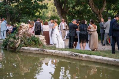 Façade d'un bâtiment illuminée par des motifs colorés, avec guirlandes lumineuses et leur reflet dans un plan d'eau.