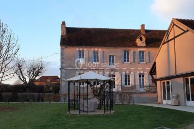 Façade d'un bâtiment avec des portes en bois et des fenêtres à volets, sous un ciel bleu dégagé.