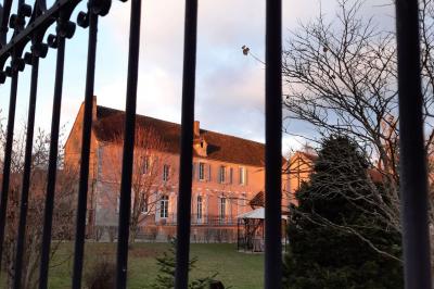 Façade d'un bâtiment avec des portes en bois et des fenêtres à volets, sous un ciel bleu dégagé.
