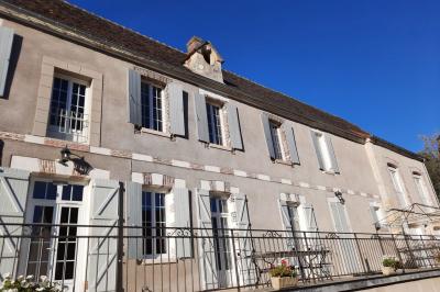 Façade d'un bâtiment avec des portes en bois et des fenêtres à volets, sous un ciel bleu dégagé.