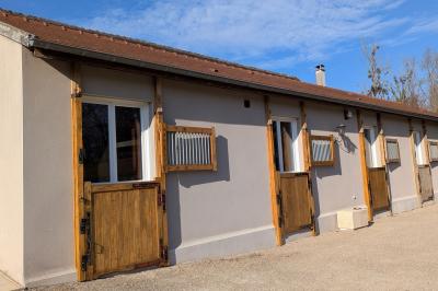 Façade d'un bâtiment avec des portes en bois et des fenêtres à volets, sous un ciel bleu dégagé.
