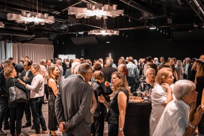 Des personnes jouent à la pétanque sur un terrain en plein air, entouré de verdure.