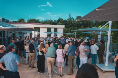 Des personnes jouent à la pétanque sur un terrain en plein air, entouré de verdure.
