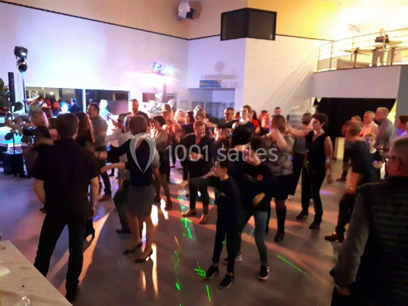 Des personnes dansent dans une salle éclairée par des lumières colorées lors d'un événement festif.