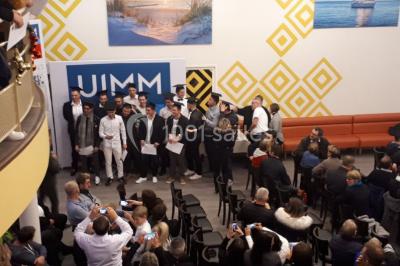 Miniature Location salle Saint-Contest (Calvados) - L'Essentiel #14 Salle comble avec des participants assis et debout lors d'un événement, décorée avec un sapin de Noël et des tableaux muraux.