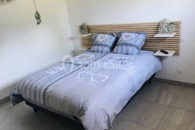 Bancs en bois disposés en extérieur, ornés de sacs en papier, avec une table blanche en arrière-plan près d'un étang.