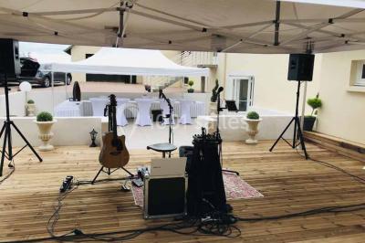 Bancs en bois disposés en extérieur, ornés de sacs en papier, avec une table blanche en arrière-plan près d'un étang.