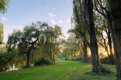 Bancs en bois disposés en extérieur, ornés de sacs en papier, avec une table blanche en arrière-plan près d'un étang.