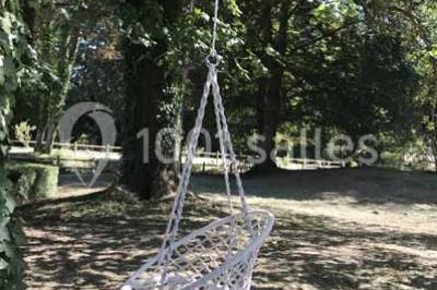 Bancs en bois disposés en extérieur, ornés de sacs en papier, avec une table blanche en arrière-plan près d'un étang.