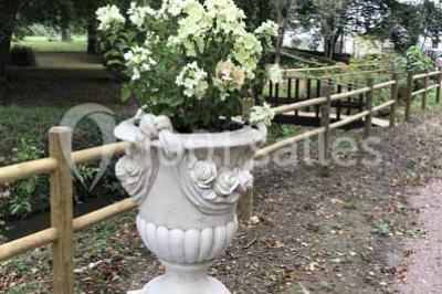 Bancs en bois disposés en extérieur, ornés de sacs en papier, avec une table blanche en arrière-plan près d'un étang.