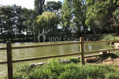 Bancs en bois disposés en extérieur, ornés de sacs en papier, avec une table blanche en arrière-plan près d'un étang.
