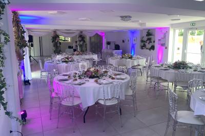 Bancs en bois disposés en extérieur, ornés de sacs en papier, avec une table blanche en arrière-plan près d'un étang.