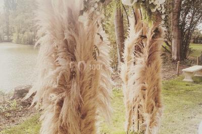Bancs en bois disposés en extérieur, ornés de sacs en papier, avec une table blanche en arrière-plan près d'un étang.