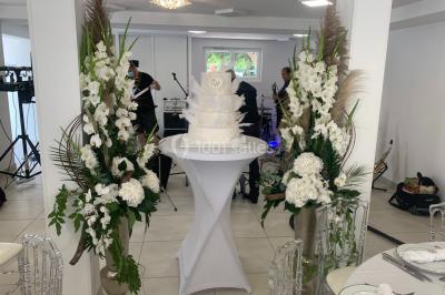 Bancs en bois disposés en extérieur, ornés de sacs en papier, avec une table blanche en arrière-plan près d'un étang.