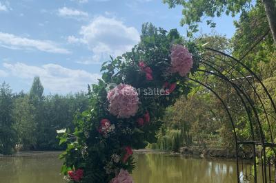 Bancs en bois disposés en extérieur, ornés de sacs en papier, avec une table blanche en arrière-plan près d'un étang.