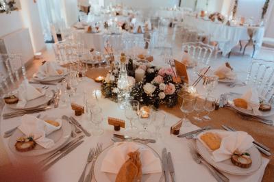 Bancs en bois disposés en extérieur, ornés de sacs en papier, avec une table blanche en arrière-plan près d'un étang.