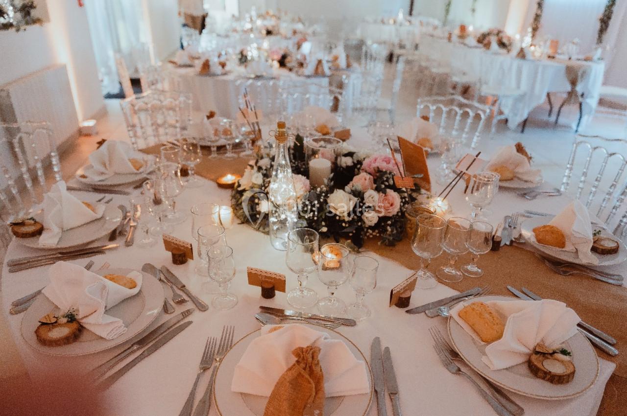 Table de réception élégamment dressée avec nappes blanches, vaisselle raffinée et centre de table floral.