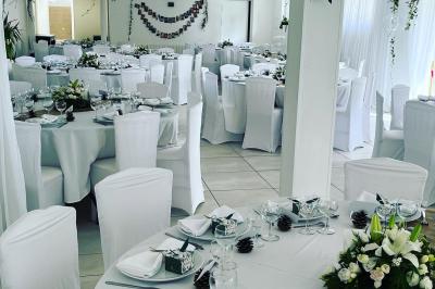 Bancs en bois disposés en extérieur, ornés de sacs en papier, avec une table blanche en arrière-plan près d'un étang.