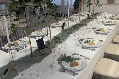 Bancs en bois disposés en extérieur, ornés de sacs en papier, avec une table blanche en arrière-plan près d'un étang.