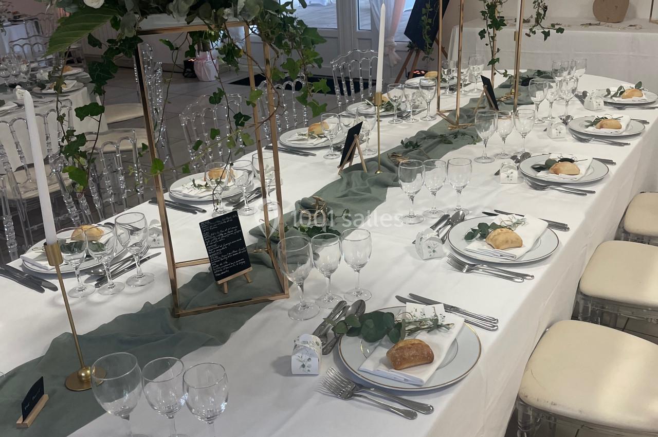 Table de réception élégamment dressée avec nappes blanches, centres de table fleuris et vaisselle raffinée.