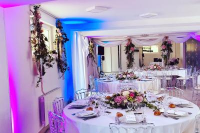 Bancs en bois disposés en extérieur, ornés de sacs en papier, avec une table blanche en arrière-plan près d'un étang.