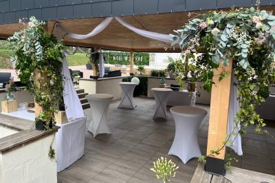 Bancs en bois disposés en extérieur, ornés de sacs en papier, avec une table blanche en arrière-plan près d'un étang.