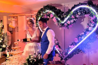 Bancs en bois disposés en extérieur, ornés de sacs en papier, avec une table blanche en arrière-plan près d'un étang.