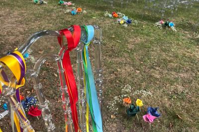 Bancs en bois disposés en extérieur, ornés de sacs en papier, avec une table blanche en arrière-plan près d'un étang.