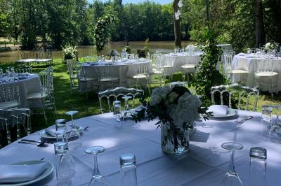 Bancs en bois disposés en extérieur, ornés de sacs en papier, avec une table blanche en arrière-plan près d'un étang.