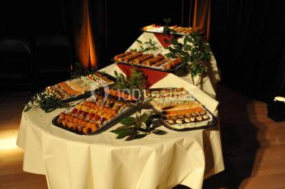 Plateaux de petits fours variés disposés sur une table ronde, décorée de feuillage, dans une ambiance tamisée.