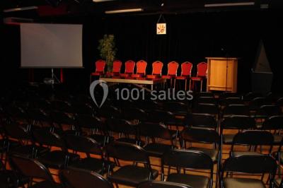 Plateaux de petits fours variés disposés sur une table ronde, décorée de feuillage, dans une ambiance tamisée.