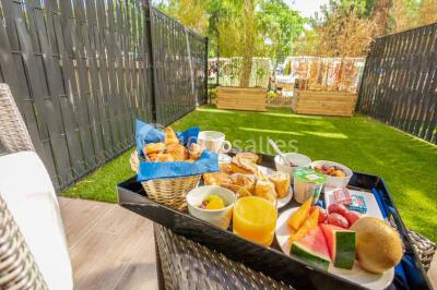 Quatre fauteuils noirs avec coussins clairs entourent une table basse dans une pièce décorée de cadres et luminaires…
