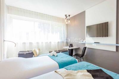 Quatre fauteuils noirs avec coussins clairs entourent une table basse dans une pièce décorée de cadres et luminaires…