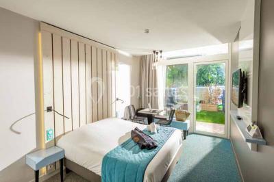 Quatre fauteuils noirs avec coussins clairs entourent une table basse dans une pièce décorée de cadres et luminaires…