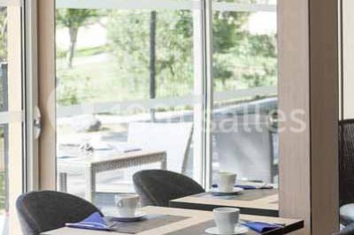 Quatre fauteuils noirs avec coussins clairs entourent une table basse dans une pièce décorée de cadres et luminaires…