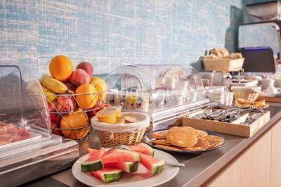Quatre fauteuils noirs avec coussins clairs entourent une table basse dans une pièce décorée de cadres et luminaires…