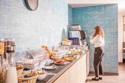 Quatre fauteuils noirs avec coussins clairs entourent une table basse dans une pièce décorée de cadres et luminaires…