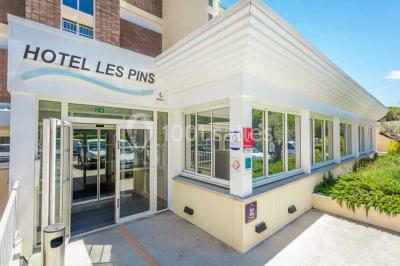 Quatre fauteuils noirs avec coussins clairs entourent une table basse dans une pièce décorée de cadres et luminaires…