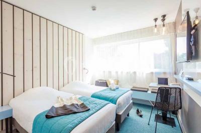 Quatre fauteuils noirs avec coussins clairs entourent une table basse dans une pièce décorée de cadres et luminaires…