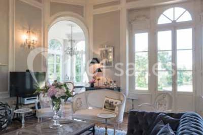 Commode rouge surmontée de cadres, lampe noire et carafe, avec un mur en pierre en arrière-plan.